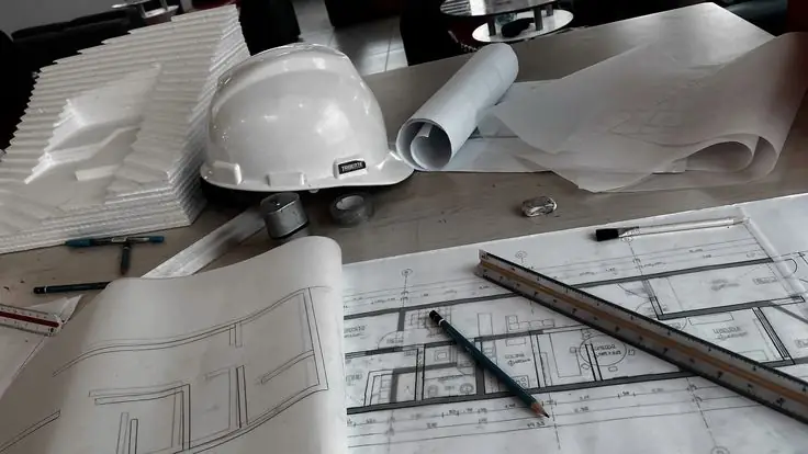 Construction planning with technical drawings and safety helmet